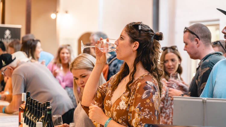 A woman sipping wine at a festival.