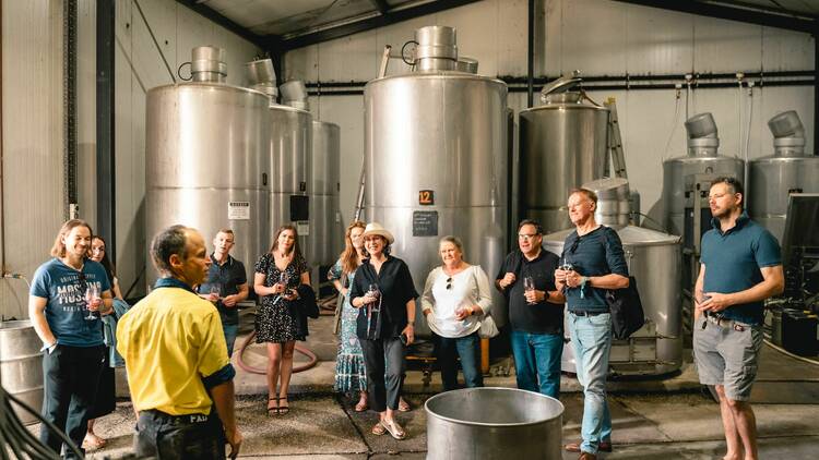 A group of people standing a wine distillery.