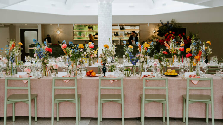 inside the Terrace event space there are long tables filled with decorations and flowers and green chairs