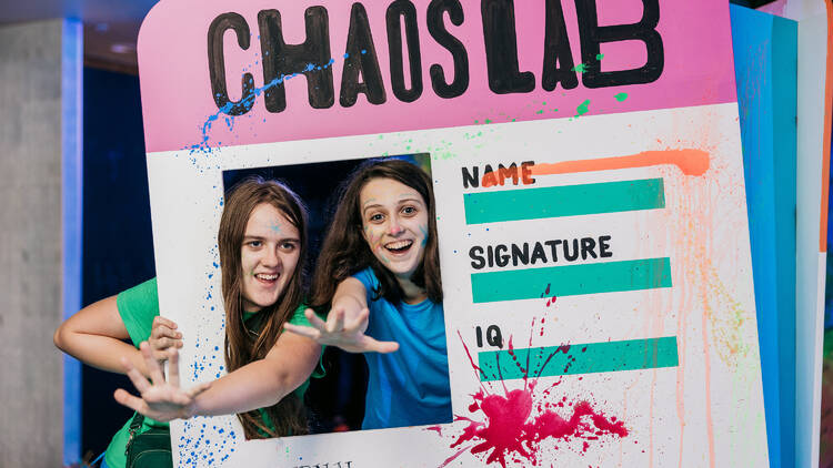 Two young girls holding a large fake paper ID with the words Chaos Lab.