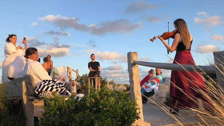 A group of musicians playing instruments on a beach.