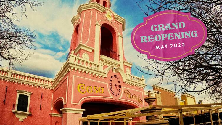 The pink towered restaurant looms before a cloudy blue sky, with the fountain in front covered in scaffolding.