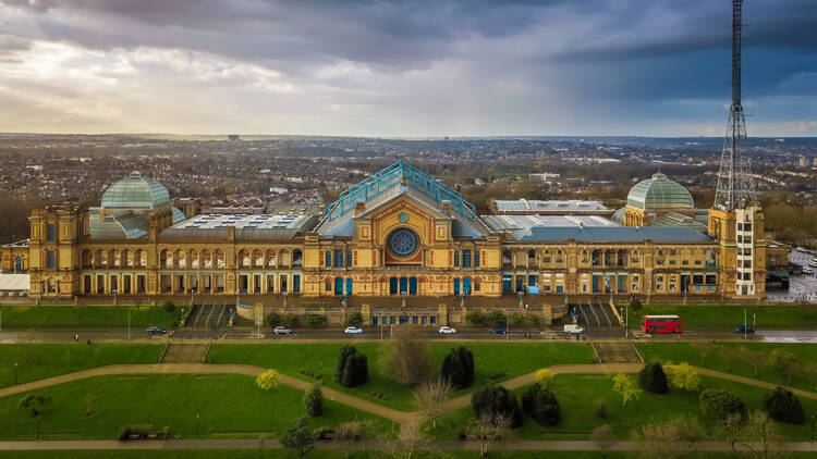 London, England - Aerial panromaic view of Alexandra Palace in Alexandra Park with iconic red double-decker bus and dramatic clouds behind