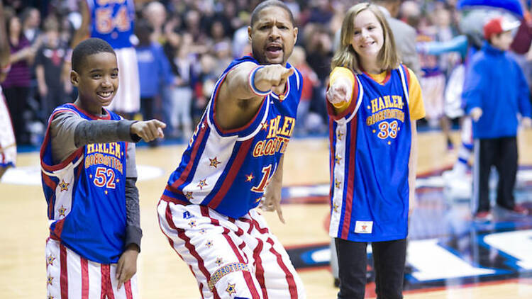 A Harlem Globetrotter and two kids pointing.