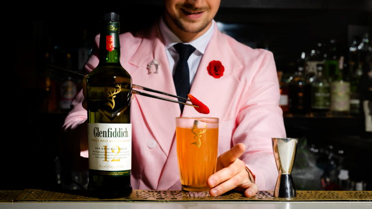 Barman wearing pink jacket making cocktail with bottle of Glenfiddich.