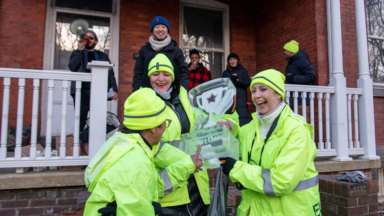 A group of people hold up a trophy made of ice.