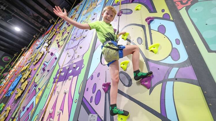 A young boy doing indoor rock climbing