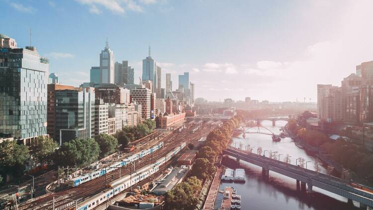 An aerial shot of Melbourne featuring buildings, the Yarra River and trains.