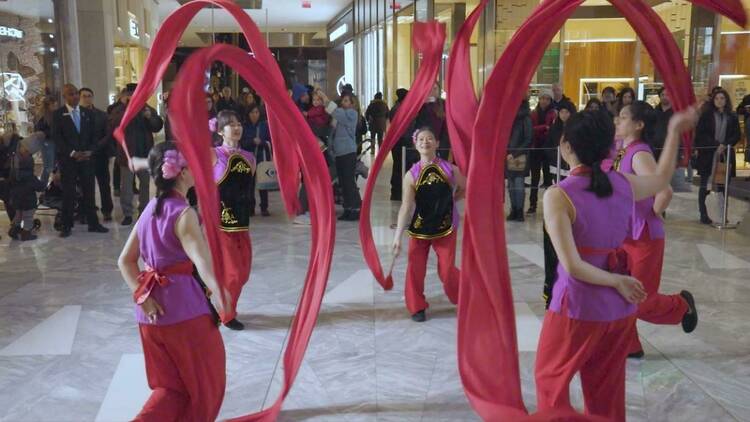 Five performers spin red ribbons in the air.