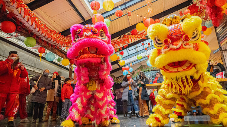 A lion dance performance with lions in pink and yellow costumes.