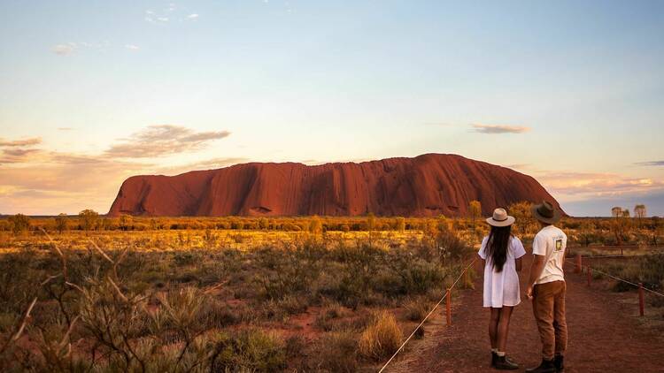 Two people looking at Uluru at sunset.