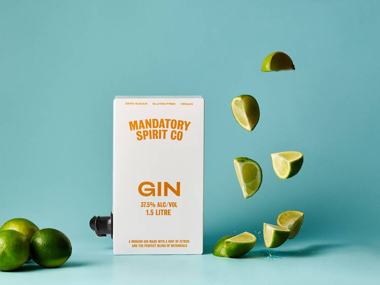 A box of gin with cut limes next to it. 