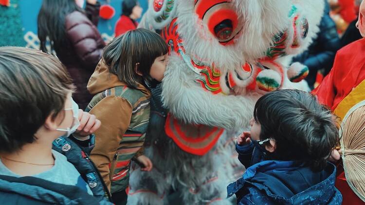 Kids hug a person wearing a lion costume.