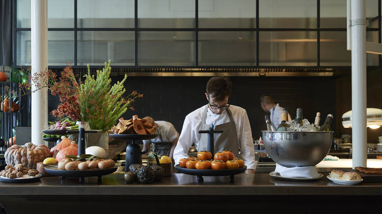 Inside Cutler and Co there is a bench topped with platters of food and drinks and a chef standing behind the bar