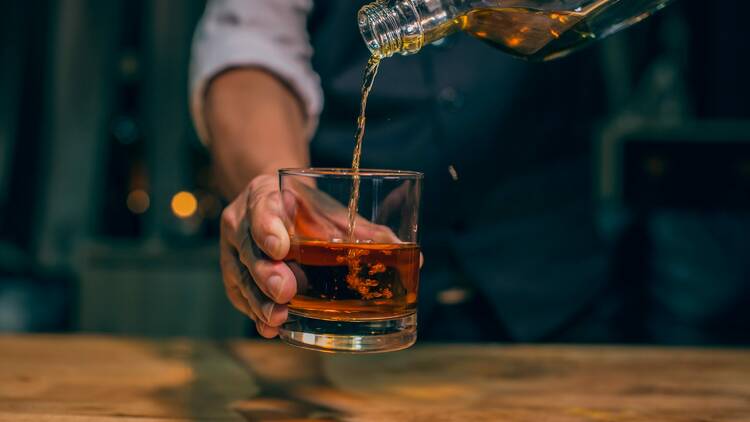 A person pouring whiskey into a glass.