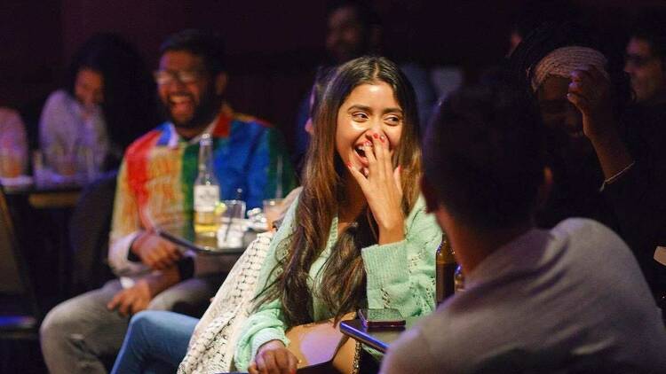 A woman laughs at a joke during Laughing Lassi.