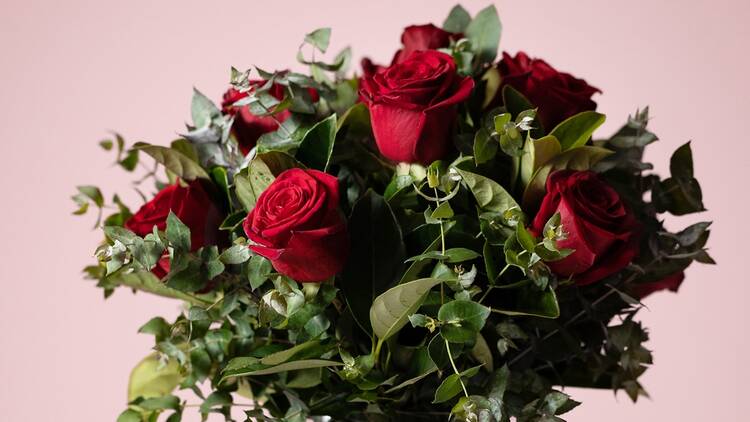 A bunch of red roses with greenery