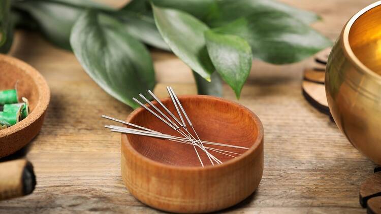 A bamboo bowl filled with acupuncture needles.