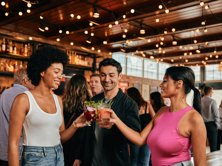 Three people cheers'ing their cocktails