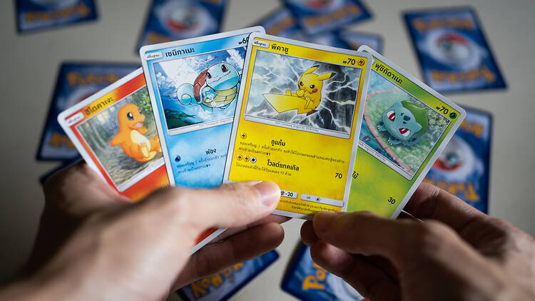 Hands holding a deck of Pokémon cards.