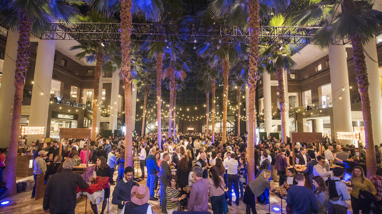 People drinking beers underneath palm trees at Brookfield Place. 