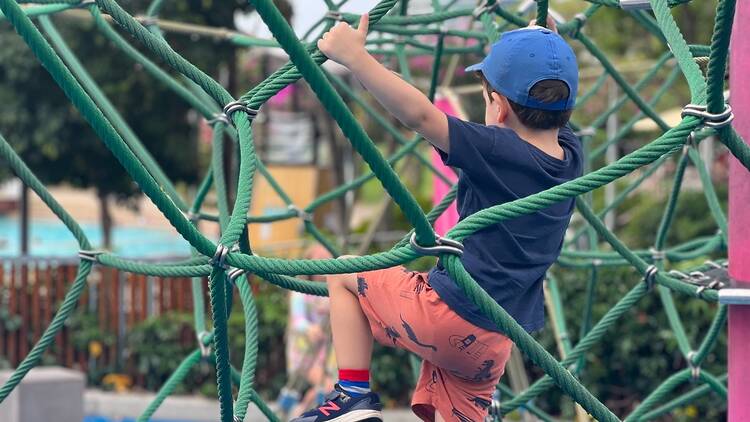 A child climbing at Riverside Green Playground
