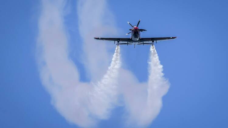 A plane flying through the sky and leaving trails.