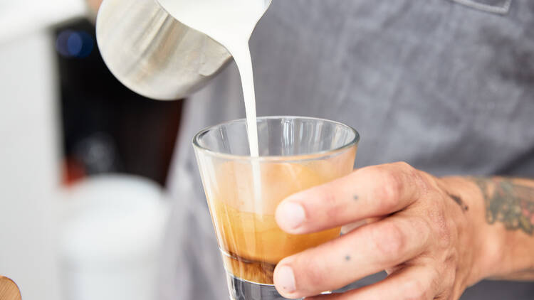 A barista pouring coffee into a cup.