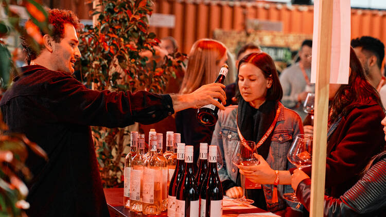 A bartender pouring wine into glasses.