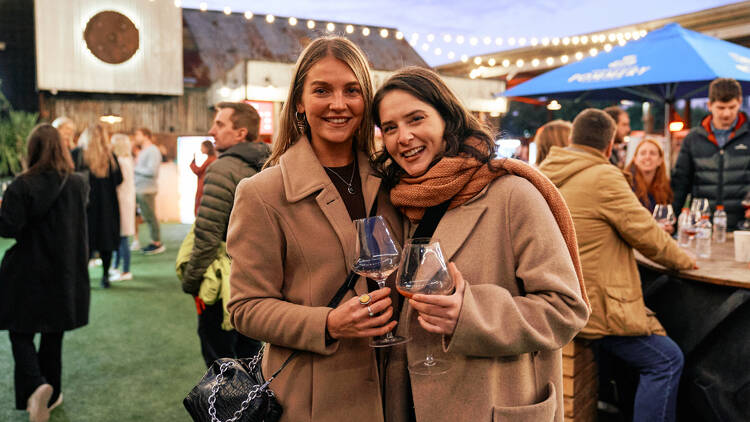 Two women holding wine glasses at a drinks festival.