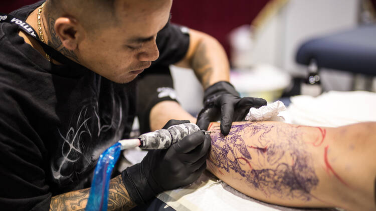 A man giving a client a tattoo.