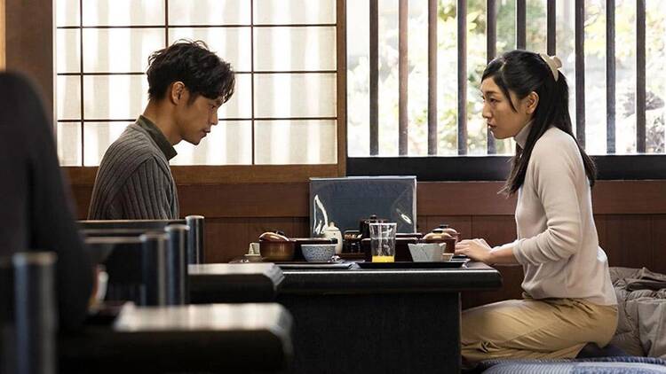 A still from the movie "A Man" shows two people dining.