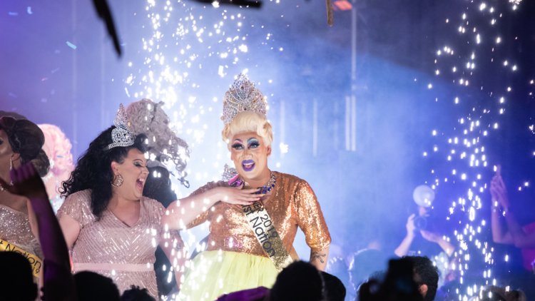 A drag queen on stage for Miss First Nation surrounded by sparks