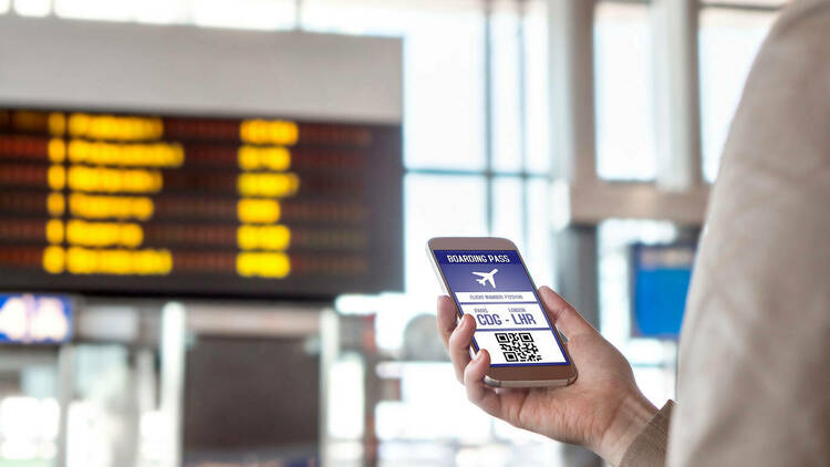 Boarding pass in smartphone. Woman holding phone in airport with mobile ticket on screen.
