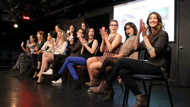 More than a dozen women sit on tall chairs on stage as part of The Female Gaze show.