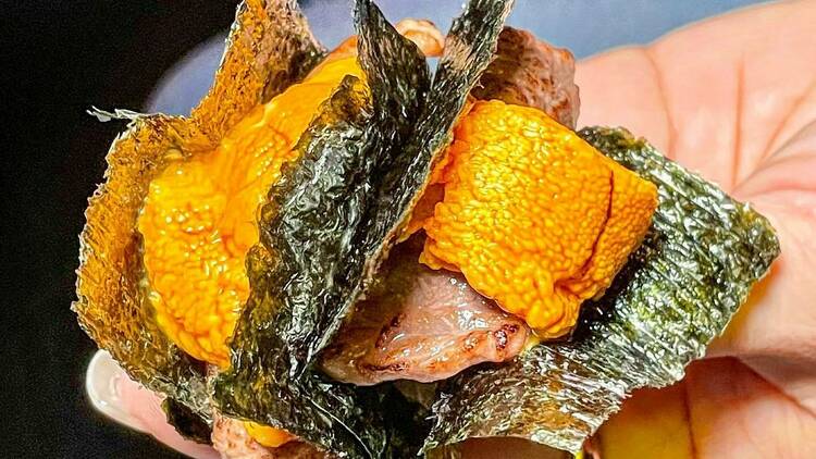 Two pieces of uni over wagyu, wrapped in seaweed