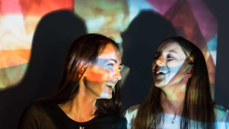 Young girls laugh in rainbow light 