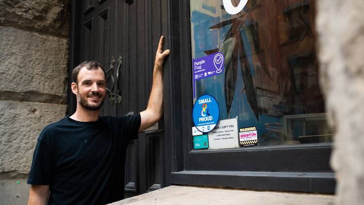 Person standing in the doorway of a venue with a purple sticker on the window.