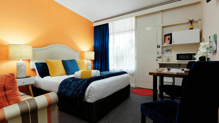 An example of the room interior at Oval Motel, with bright yellow and blue accents.