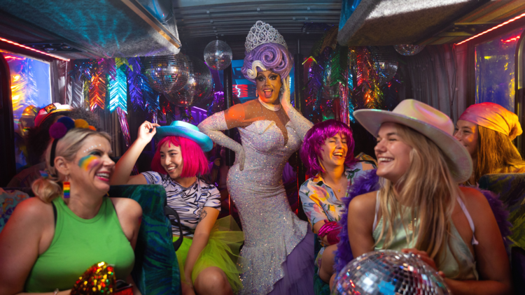 People laughing inside a colourful party bus for Pride