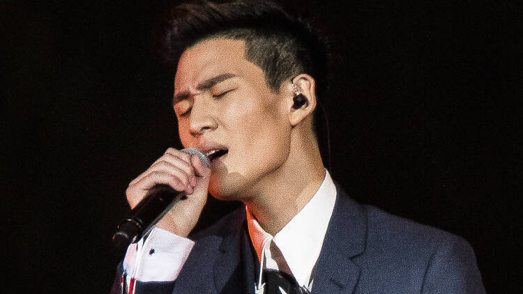 Singer Eric Chou singing on stage with a microphone.