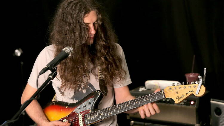 Singer Kurt Vile playing guitar on stage.