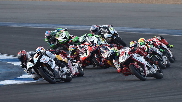 A group of people competing in a motorcycle race.