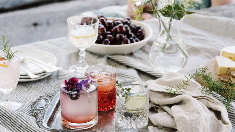 A few glasses of gin on a table with fresh fruit.