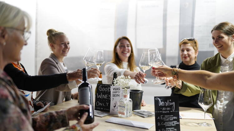 Women toast wine glasses around a table at Fashion + Food Zurich.