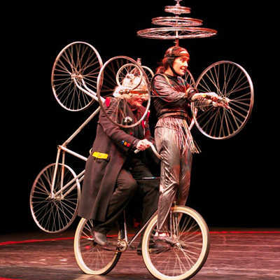 Escena de Le Cirque Invisible con los actores subidos a una bicicleta con muchas ruedas