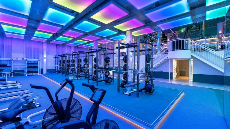 A gym that looks more like a nightclub, with coloured light panels on the ceiling.