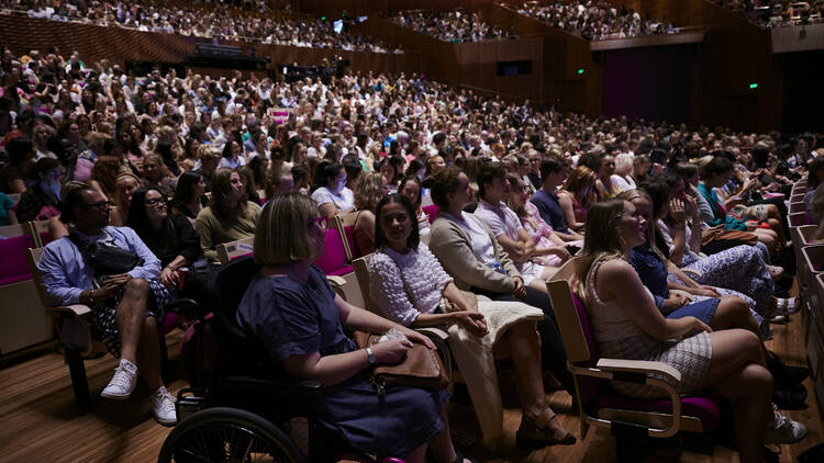 A huge crowd of people sitting in a Sydney Opera House auditorium.