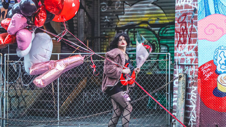 Tammy Faymous walks a dog while carrying balloons.