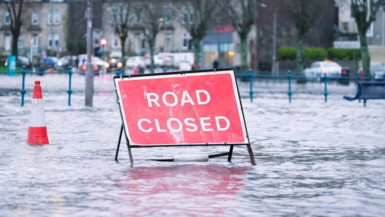 A flooded road and a sign with the words 'road closed' 